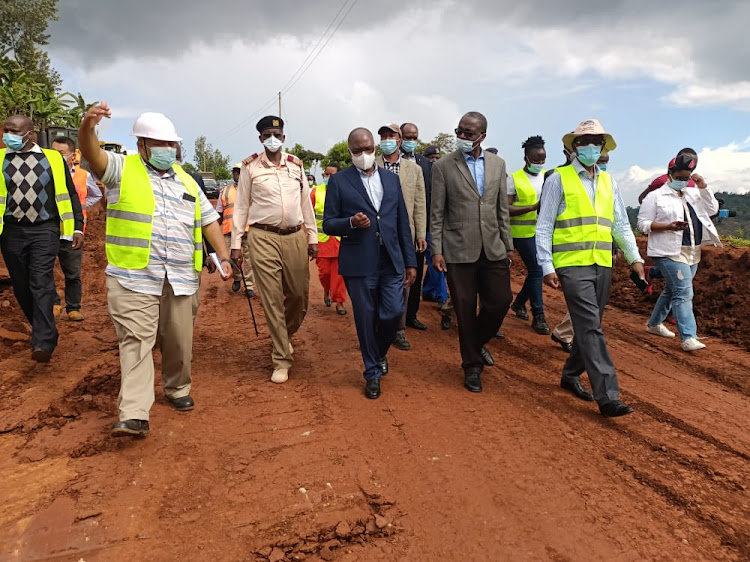 Transport Cabinet Secretary James Macharia (in black suit) leads a team of government officials in inspecting part of the Mau Mau roads project at Kiamara in Kangema last Friday.