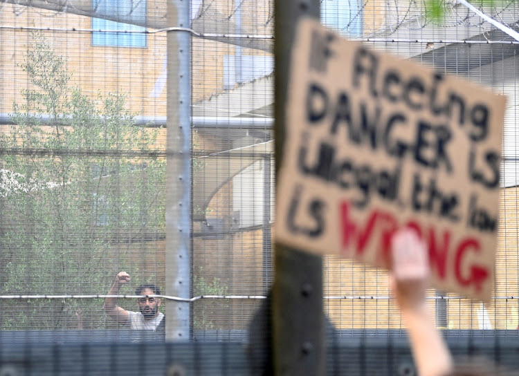 A detainee inside Brook House Immigration Removal Centre gestures as demonstrators protest against a planned deportation of asylum seekers from Britain to Rwanda, at Gatwick Airport near Crawley, Britain, June 12 2022. Picture: TOBY MELVILLE/REUTERS