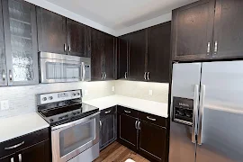 Kitchen featuring dark wood cabinets, stainless steal appliances, and title backsplash 