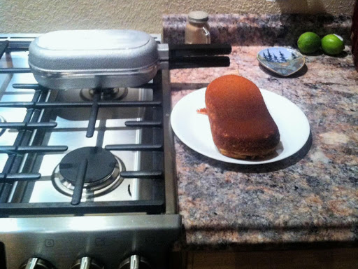 Loaf of cornbread with a vintage double omelet fry pan in the background.