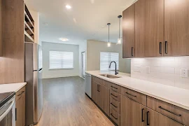 Kitchen with dark cabinets, wood-inspired flooring, white countertops, light walls, and stainless steel appliances