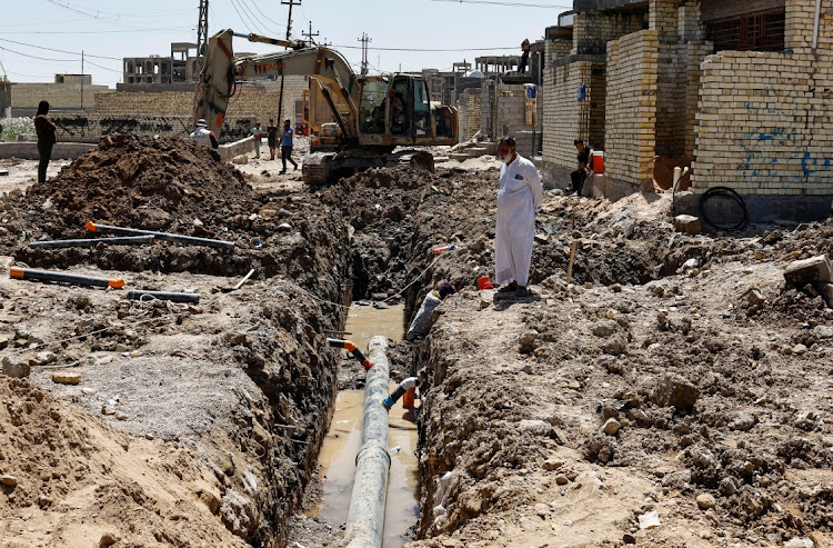 Iraqi workers place a storm sewer pipe into a trench on the outskirts of Sadr city district of Baghdad,Iraq May 1, 2023. The government has kicked off the largest effort to refurbish Baghdad since the 2003 U.S invasion, including renovating the facades of buildings damaged by war and revamping parks and promenades that hug the Tigris River that bisects the city. REUTERS/THAIER AL-SUDANI