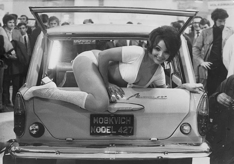 Model Julie Desmond climbs out of the back of a Russian Moskvich 427 car, at a car trade show in 1971.