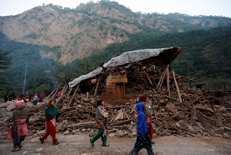 People walk along the house collapsed during the earthquake in Rukum, Nepal November 5, 2023.