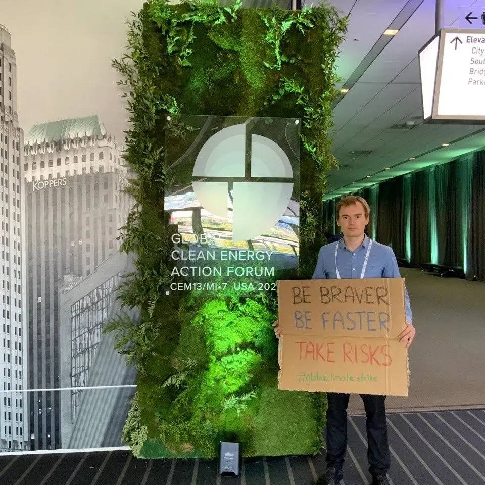 UNFCC Jugenddelegierter Michael Spiekermann protestiert mit einem Schild vor dem Clean Energy Action Forum in Pittsburgh. Auf dem Schild steht: Be braver, be faster, take risks.