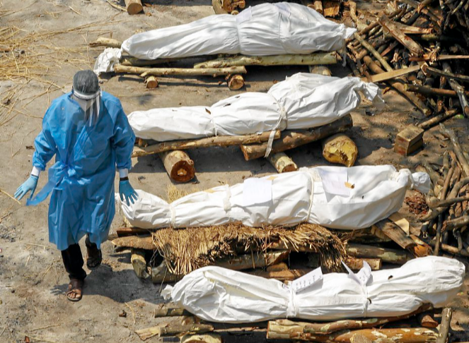 A health worker walks past a row of bodies of Covid-19 victims waiting to be cremated in New Delhi, India. Picture: REUTERS/ADNAN ABIDI