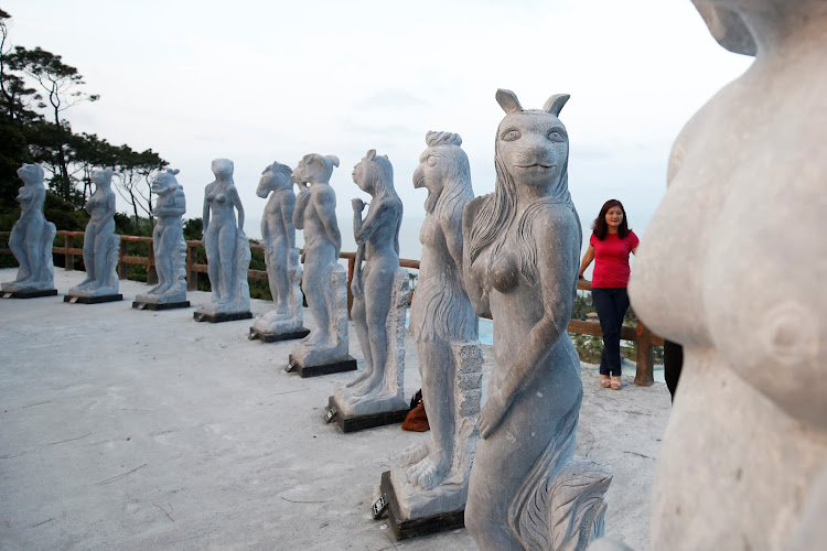 A woman stands near godlike sculptures with animal heads and human genitalia at Hon Dau resort in Hai Phong city, east of Hanoi, Vietnam April 5, 2018.