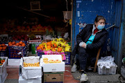 A woman wearing a face mask sits next to a fruit stall at a residential area after the lockdown was lifted in Wuhan, capital of Hubei province and China's epicentre of the Covid-19 outbreak, on April 11 2020.