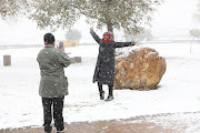 Thembi Jeja takes photographs out in the snow, 10 July 2023, at Jackson Dam in Alberton, South of Johannesburg.  Gauteng residents were surprised when large parts of the province experienced snow following a cold front that made its way over the province the night before. 