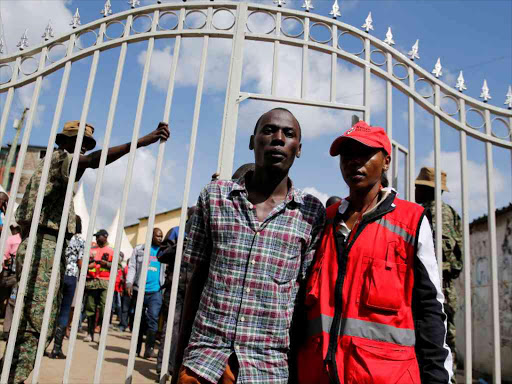 Ralson Saisi Wasike, father to Dealeryn Saisi Wasike, a baby girl rescued from the rubble of a six-storey building that collapsed after days of heavy rains, is escorted by a Kenya Red Cross staff after addressing a news conference in Nairobi yesterday.Photo Reuters