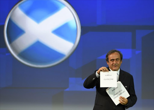 UEFA President Michel Platini holds up the card for Glasgow who will host a round of 16 and group stage matches of the 2020 UEFA European championship in Geneva on September 19, 2014.