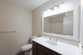 Bathroom with light walls, trim and counter with a dark vanity with lower cupboards & drawers with a mirror & vanity lights.