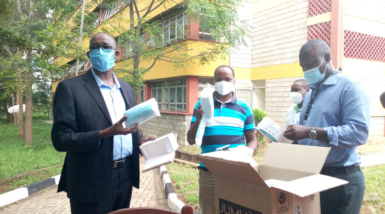 Makueni county commissioner Maalim Mohammed and Health CEC Andrew Mulwa inspect surgical masks donated by Amref outside the county commissioner’s office in Wote town