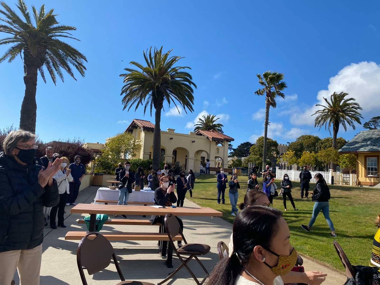 May be an image of one or more people, people standing, outdoors and palm trees