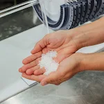 Two hands cup a pile of salt over a machine designed by the Malta team that can store renewable energy in molten salt