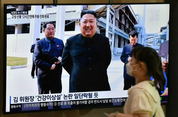 A woman walks past a television news screen showing a picture of North Korean leader Kim Jong Un attending a ceremony to mark the completion of Sunchon phosphatic fertiliser factory, at a railway station in Seoul on May 2, 2020. Picture: AFP/JUNG YEON-JE