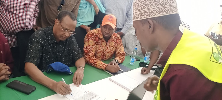 Former Garissa governor Nathif Jama and running mate Abdi Dagane sign documents during his clearance by the IEBC at the Garissa University on Saturday, June 4.