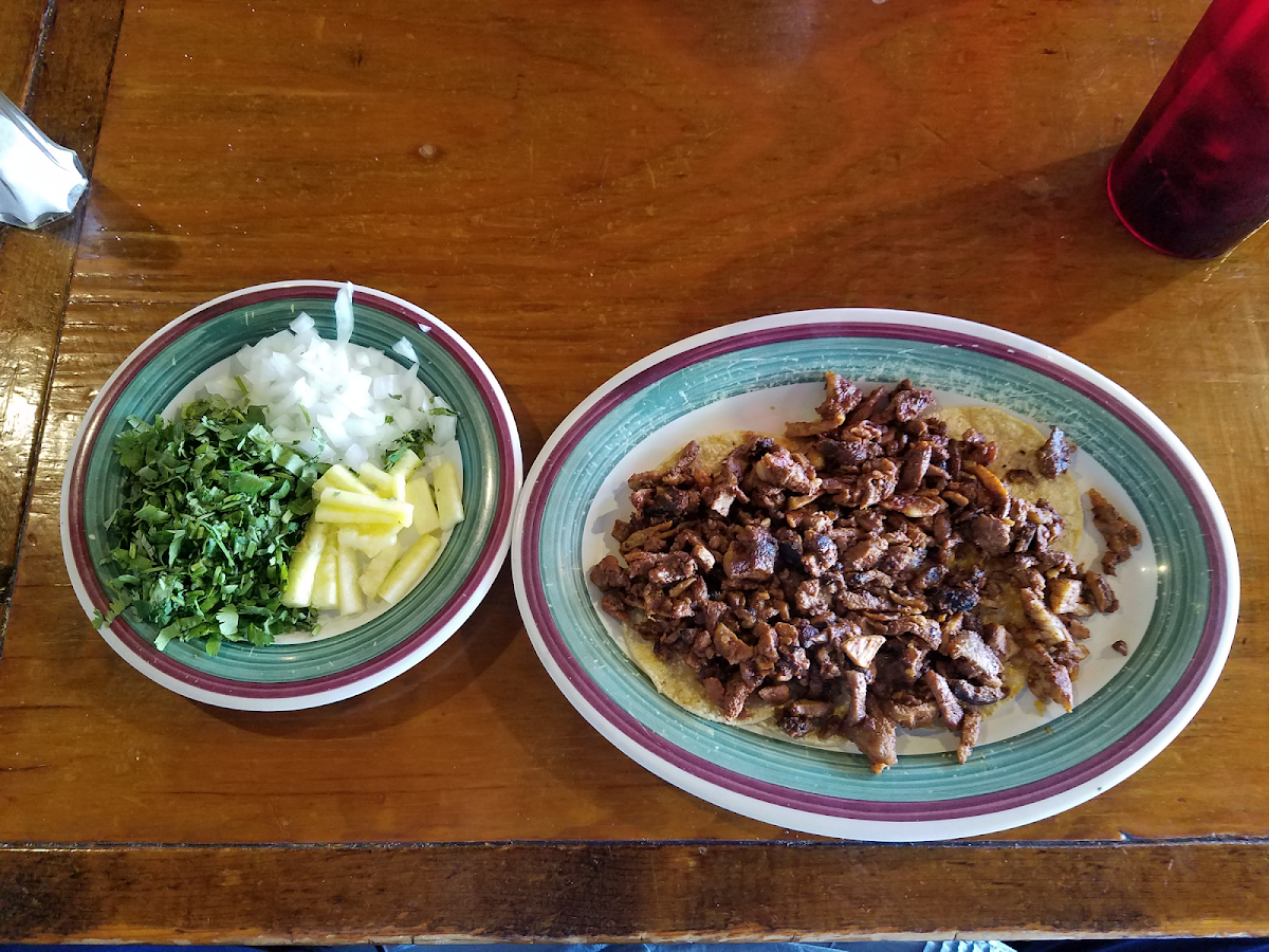 Delicious mini tacos al pastor with onion, cilantro and pineapple.