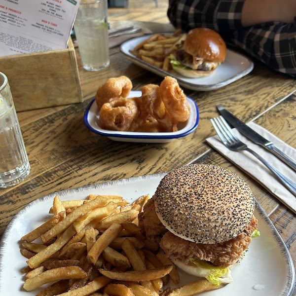 Gluten free chicken burger from the lunch menu (front). Regular beef burger (back). Gluten free onion rings.