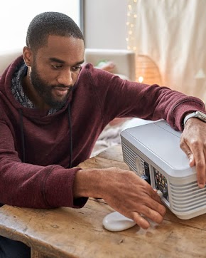 A man plugging in Chromecast into the back of a projector.