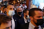 Israeli Prime Minister Benjamin Netanyahu surrounded by bodyguards as he visits Mahane Yehuda market, a day before the March 23 general election, in Jerusalem March 22, 2021. 