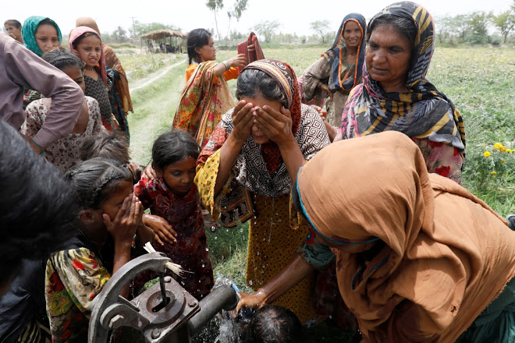 Women and children wash themselves after work at a muskmelon farm, during a heatwave, at a hand pump on the outskirts of Jacobabad, Pakistan, May 17, 2022.