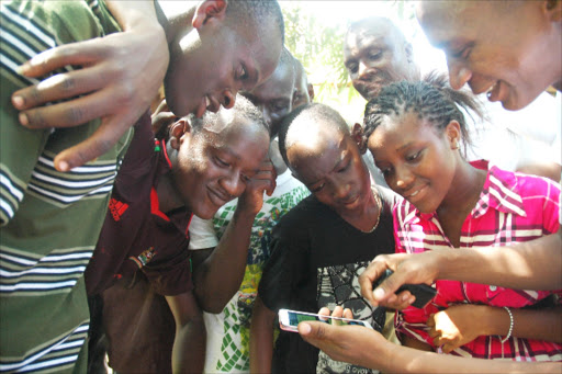 St Kevin Hill School Nyali former students check their KCPE results on phone at the school in Mombasa yesterday. Education CS Jacob Kaimenyi released the results yesterday with mixed reactions from education stakeholders over governments move to abolish ranking of students and schools in national examinations. Photo Andrew Kasuku