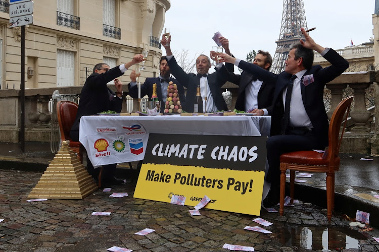 Climate activists disguised as CEOs of major oil companies take part in a fake banquet celebrating profits, in call on states taking part in COP28 climate conference to finance loss and damage fund by taxing fossil fuel profits, near the Eiffel Tower in Paris, France, November 27, 2023.