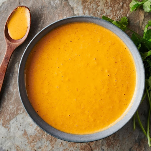 A gray ceramic bowl filled with a vibrant orange sauce.