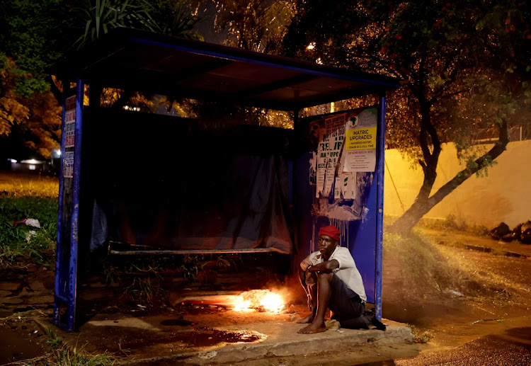 Goodman Mhlongo warms himself by a fire as he prepares to sleep in a bus shelter on Botanic Gardens Road in Durban.