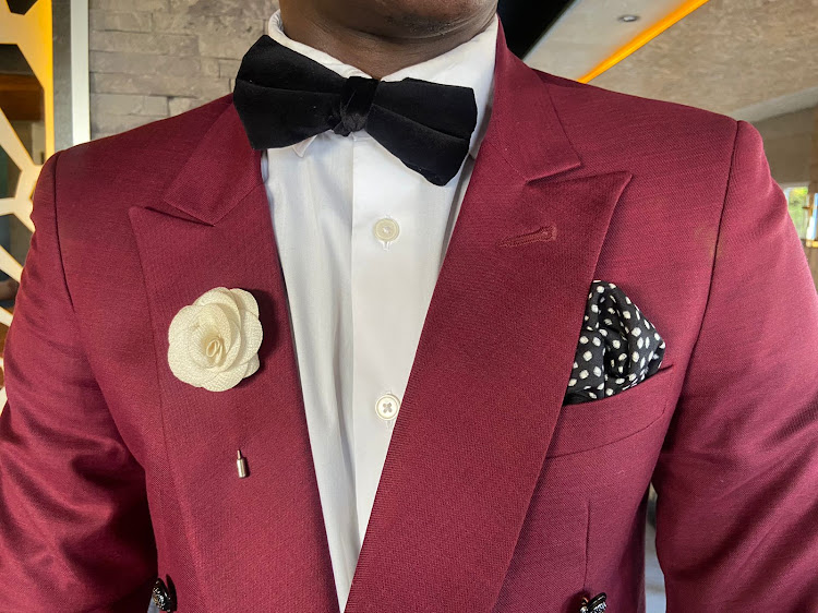 A man wears a beige lapel, polka dot pocket square on a maroon suit