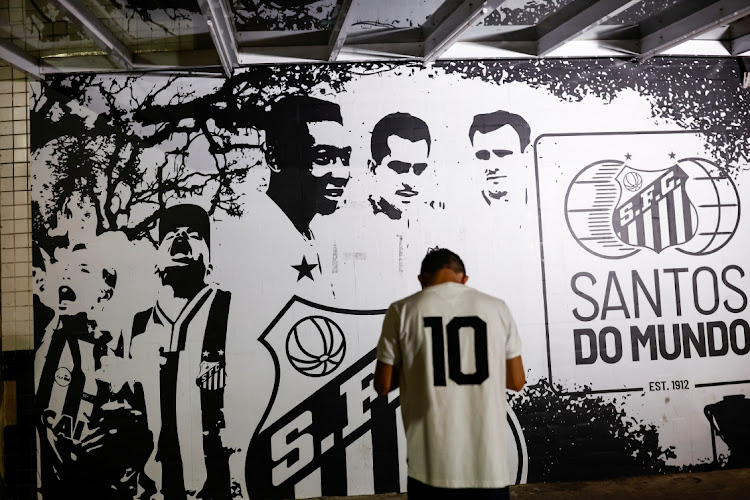 A person stands in front of an image depicting Brazilian soccer legend Pele as people gather to mourn his death, in Santos, Brazil on December 29 2022. Picture: REUTERS/AMANDA PEROBELLI