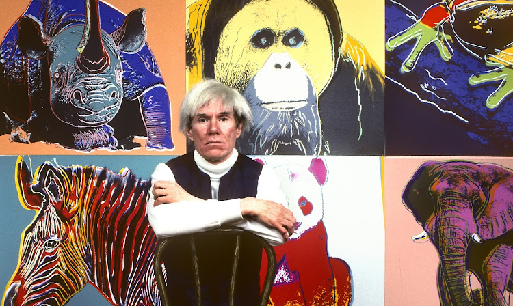 American artist Andy Warhol sits in front of several paintings in his 'Endangered Species' series at his New York studio, the Factory, on April 12 1983.