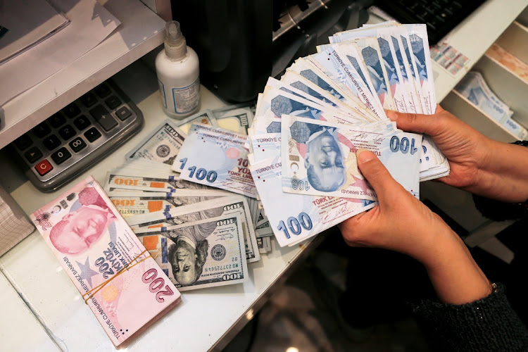 A money changer holds Turkish lira banknotes at a currency exchange office in Ankara, Turkey. Picture: CAGLA GURDOGAN/REUTERS