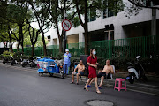 Topless men sit on chairs on the street, at a residential area, amid a heatwave warning, in Shanghai, China July 20, 2022. 