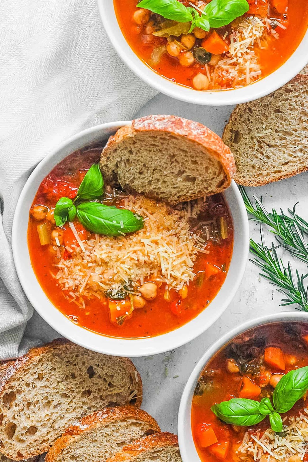 Italian chickpea soup with bread slices, cheese, and basil.