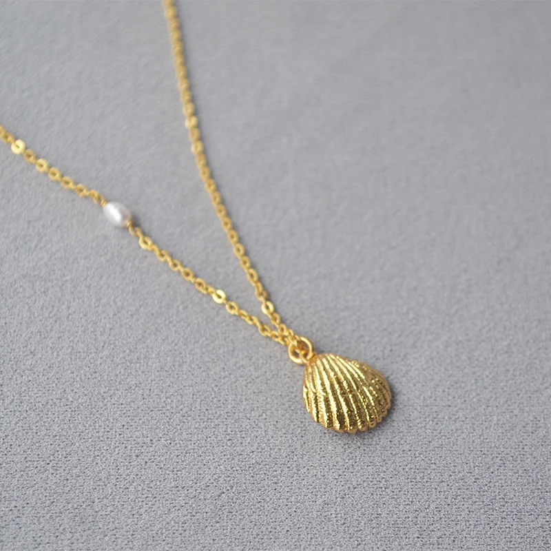 Collier minimaliste en laiton plaqué or, perle d'eau douce et coquillage doré, un bijou élégant pour un éclat subtil au quotidien.