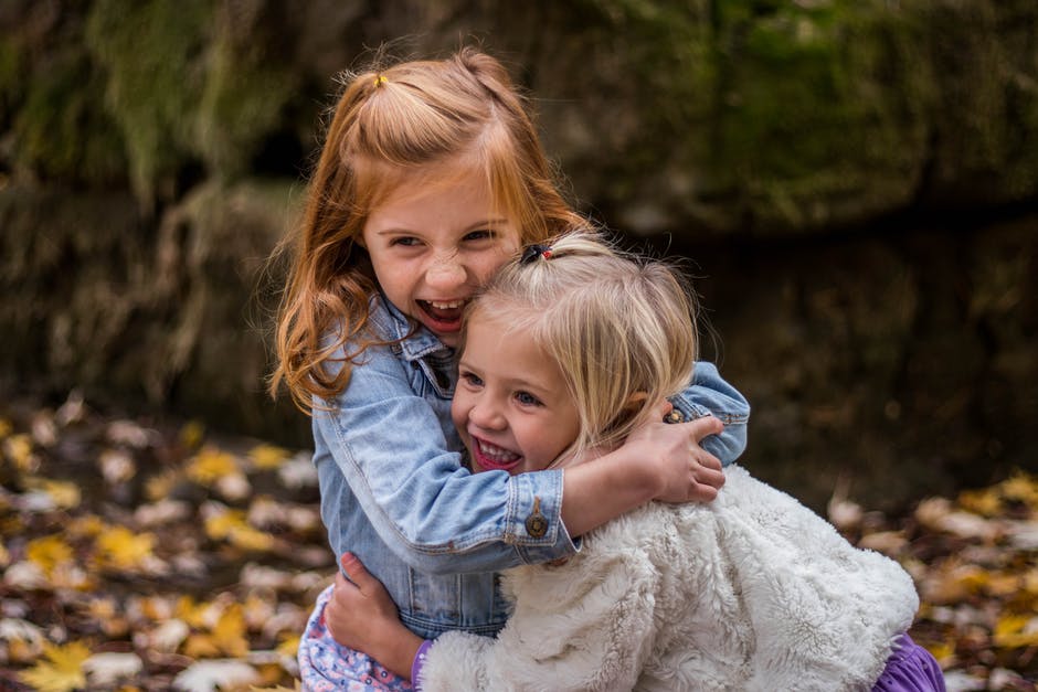 2 Girls Hugging Each Other Outdoor during Daytime