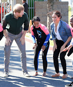 Prince Harry and Meghan, Duchess of Sussex, join the surf mentors of the NGO Waves For Change in a rhythmic call-and-response game at Monwabisi Beach on September 24 2019 in Cape Town.