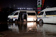 Taxi drivers try to start a minibus taxi after it was flooded in Mayville, Durban. 