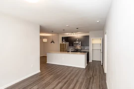 Living room facing kitchen and dining area with wood inspired floors and neutral colored walls