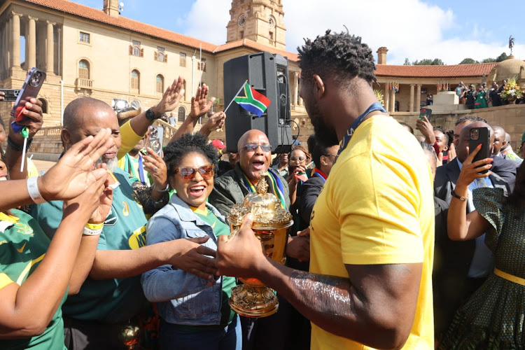 Springboks captain Siya Kolisi holding the Web Ellis Cup with some of the country's ministers