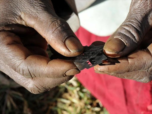 A traditional cutter in Uganda holds razor blades before carrying out female genital mutilation on girls from the Sebei tribe in Bukwa district, northeast of Kampala, December 15, 2008. /REUTERS
