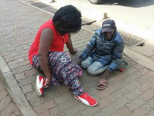 Nairobi woman representative Rachel Shebesh helps a disabled man on a street in Nairobi at the weekend. /COURTESY