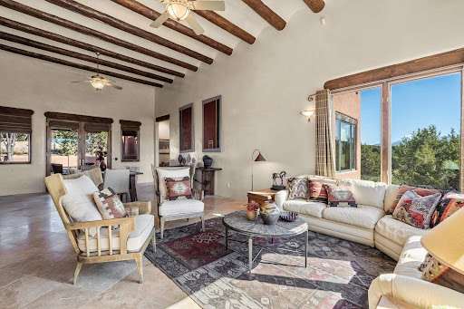 Living room with exposed beams and large windows in this luxury house for sale in Santa Fe ($1,450,000)