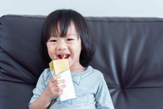 Premium Photo | Happy sweet asian baby child drinking a carton of milk from  box