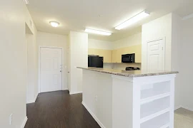 Island in the kitchen with stone inspired countertops, wood inspired flooring, and wood cabinets