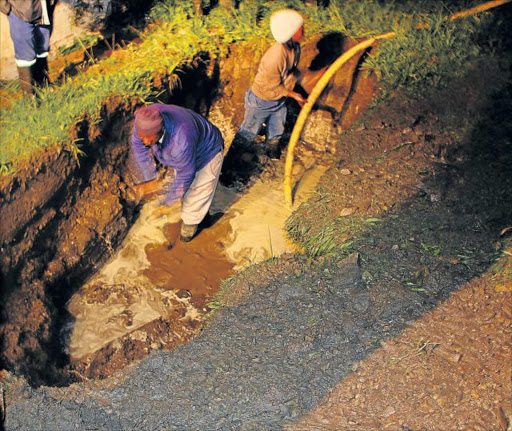 DAMAGE CONTROL: Municipal workers get to work outside a Mdantsane house that was flooded when a pipe burst on Friday, flooding the home Picture: MALIBONGWE DAYIMANI