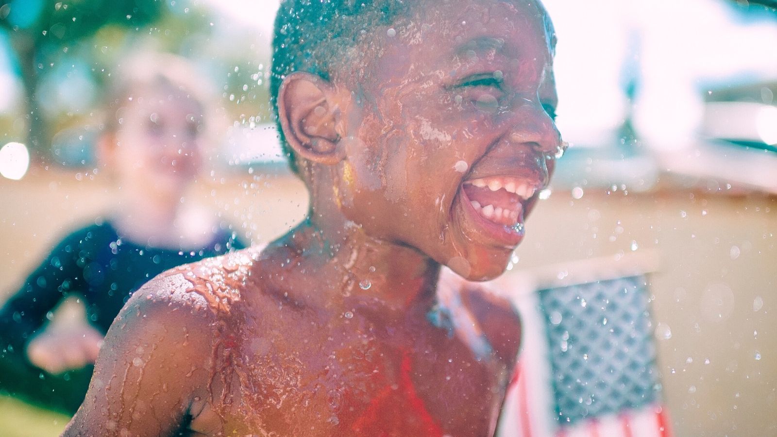 A child expresses laughter while soaked in water.