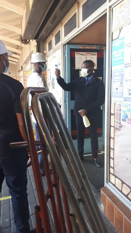 Shoppers' temperatures are taken outside a liquor store in Sophiatown, Johannesburg.